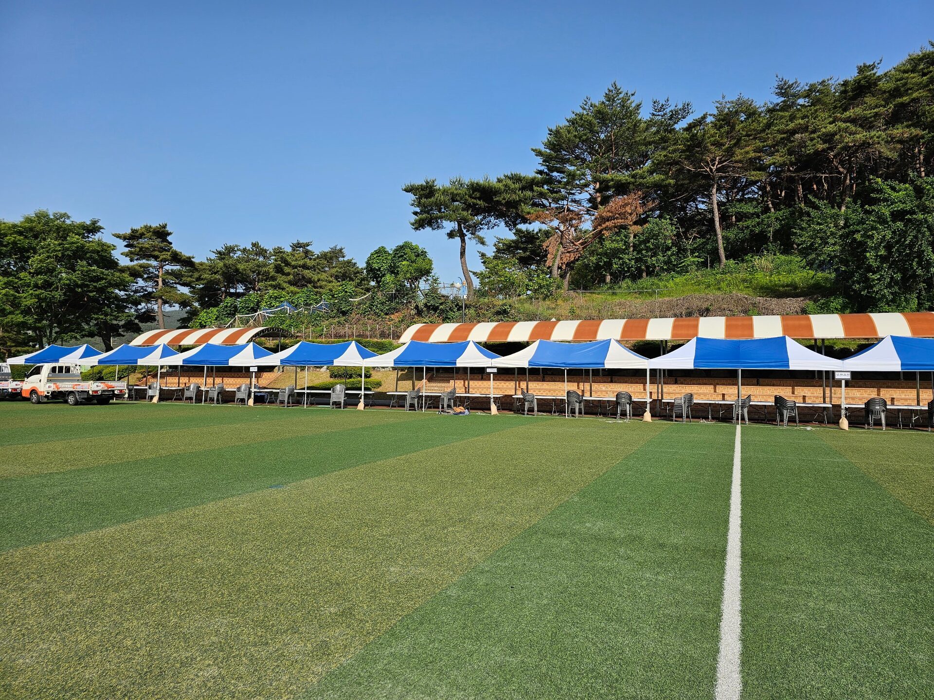 잔디 축구장 옆에 팀별로 세운 줄무늬 그늘막 천막